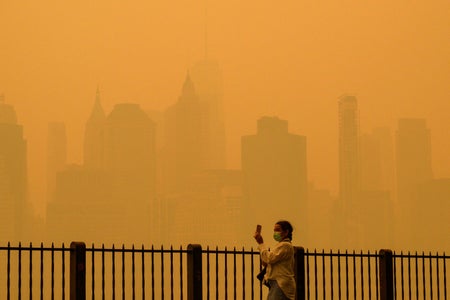 Person walking with face mask during heavy air pollution in front of NYC yellow skyline