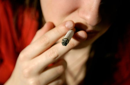 Close-up of person in red shirt smoking a cigarette