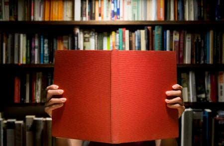 Person reading book in front of book shelf