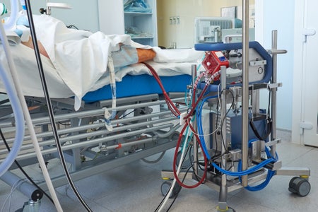 An ECMO machine next to a patient's bed in a hospital's intensive care unit