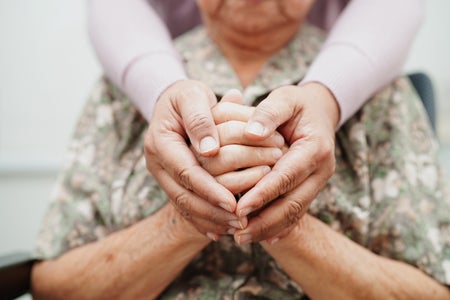 Midsection of a woman and a set of hands embracing another from the back.