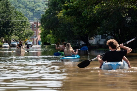 Several people kayaking in water flooding a street in downtown Montpelier, Vermont