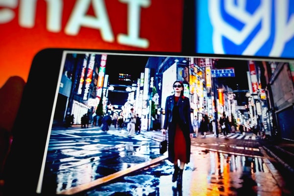 A person holding a smart phone playing video generated by Sora AI of a woman walking down a city street at night